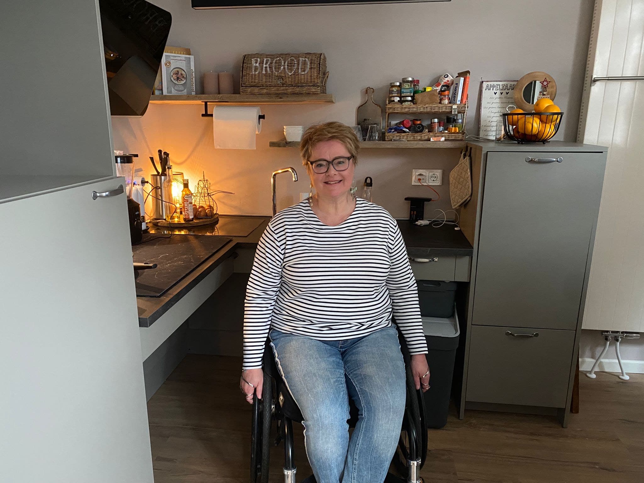 Jessica poseert in haar rolstoel in haar keuken.