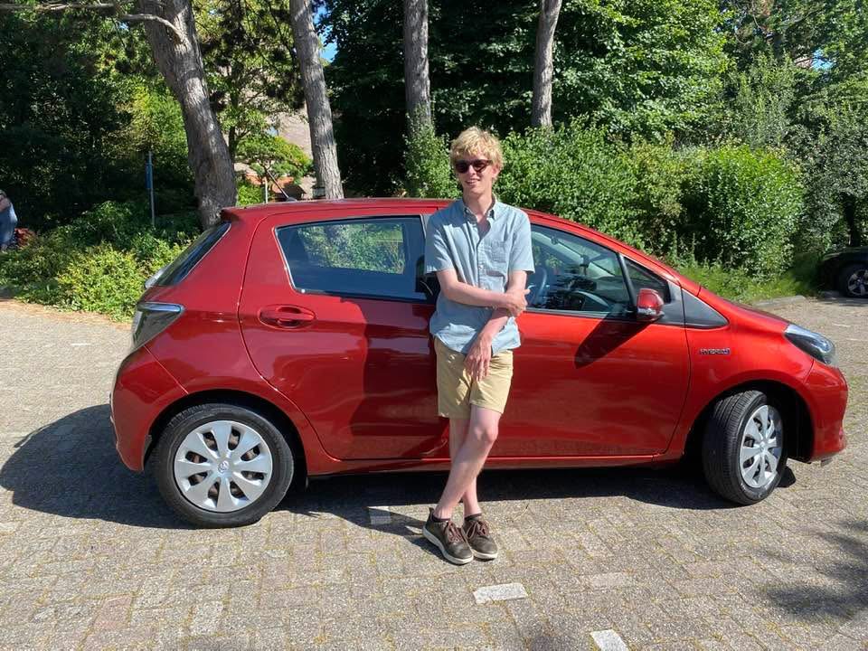 Ik poseer voor de zijkant van mijn auto in zomerkleren.